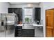 A well-lit kitchen featuring stainless steel appliances, black cabinets, and a stylish farmhouse sink at 725 Ingham Rd, New Smyrna Beach, FL 32168