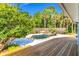 Backyard oasis featuring a pool, rock waterfall feature, lush landscaping, and a wooden deck at 725 Ingham Rd, New Smyrna Beach, FL 32168