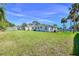 Expansive, fenced backyard with lush green grass, mature palm trees, and neighborhood views at 902 Conrad Dr, New Smyrna Beach, FL 32168