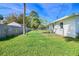 Fenced backyard with lush green grass and mature trees and a white house at 902 Conrad Dr, New Smyrna Beach, FL 32168