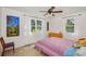 Bright bedroom filled with natural light showcasing multiple windows, a ceiling fan, and colorful bedspread at 902 Conrad Dr, New Smyrna Beach, FL 32168