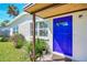 Close up of a white home with a vibrant blue front door and a well-landscaped garden at 902 Conrad Dr, New Smyrna Beach, FL 32168
