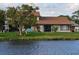 Back exterior view of a tan home by the water, showcasing the patio and serene water views at 108 Lake Fairgreen Cir, New Smyrna Beach, FL 32168