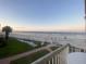 Beach view from balcony with palm trees, lawn furniture, and the ocean in the background at 111 N Atlantic Ave # A219, New Smyrna Beach, FL 32169