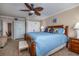 Comfortable main bedroom featuring a wooden bed frame, blue bedding, and decorative ceiling fan at 111 N Atlantic Ave # A219, New Smyrna Beach, FL 32169