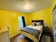 Bright bedroom with yellow walls, wood floors, closet with curtain, and a cozy bed at 1136 Elizabeth St, New Smyrna Beach, FL 32168