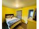 Bright bedroom with yellow walls, wood floors, closet with curtain, and comfortable bed at 1136 Elizabeth St, New Smyrna Beach, FL 32168