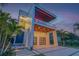 Modern home with colorful lighting, a large driveway, and meticulously maintained landscaping featuring vibrant green grass at 1194 N Peninsula, New Smyrna Beach, FL 32169