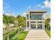 Modern two-story home featuring a balcony, stylish garage doors and a beautifully landscaped front yard with palm trees at 1194 N Peninsula, New Smyrna Beach, FL 32169