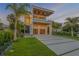 Striking modern home with a clean, white facade, covered balconies, and lush landscaping at sunset at 1194 N Peninsula, New Smyrna Beach, FL 32169
