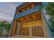 Striking modern home exterior with wood paneling and illuminated balcony at dusk at 1194 N Peninsula, New Smyrna Beach, FL 32169
