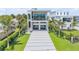 Contemporary home with a long driveway, manicured lawn, and tropical palm trees at 1194 N Peninsula, New Smyrna Beach, FL 32169