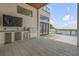 Outdoor kitchen featuring stainless steel grill, sink, and view to the pool and waterfront at 1194 N Peninsula, New Smyrna Beach, FL 32169