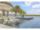 Inviting pool with in-water loungers and waterfront views with shade provided by palm trees at 1194 N Peninsula, New Smyrna Beach, FL 32169