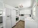 Bright kitchen featuring white cabinets and appliances, with a wood-look floor at 1208 Pat Ave, New Smyrna Beach, FL 32168