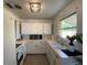 Charming kitchen features white cabinets, laminate countertops, and stainless steel faucet at 1208 Pat Ave, New Smyrna Beach, FL 32168