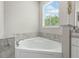 This tiled bathtub features marble styled tiling with a window view at 1290 9Th St, Orange City, FL 32763