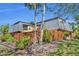 View of a multi-story home with a fence, beautiful landscaping, and mature trees at 135 Cedar Dunes Dr, New Smyrna Beach, FL 32169