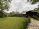 Landscaped backyard with a spacious lawn, mature trees, and a screened-in porch at 1370 Jane Lacey Ln, New Smyrna Beach, FL 32168