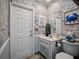 Bathroom with marine-themed wallpaper, wainscoting, white vanity, toilet, and natural light at 1370 Jane Lacey Ln, New Smyrna Beach, FL 32168