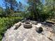 Charming outdoor fire pit area surrounded by stone benches and lush greenery, perfect for cozy gatherings and relaxation at 1370 Jane Lacey Ln, New Smyrna Beach, FL 32168