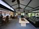 Entertaining screened porch with bar seating, outdoor kitchen, ceiling fans, and a comfortable seating area with a fire table at 1370 Jane Lacey Ln, New Smyrna Beach, FL 32168