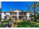 Condo with screened porches and wooden stairs in a grassy area with trees under a clear blue sky at 1600 Big Tree Rd # I2, South Daytona, FL 32119