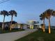 Coastal home featuring a metal roof, lush landscaping, and an inviting driveway lined with palm trees at 2019 S Riverside, Edgewater, FL 32141