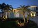 Charming home exterior featuring lush tropical landscaping and accent lighting at twilight at 2019 S Riverside, Edgewater, FL 32141