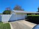 Single-story home featuring an attached garage, white fence, and manicured shrubbery at 2321 Tamarind Dr, Edgewater, FL 32141