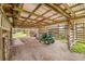 Open shed area with a tractor and lawn equipment offering covered storage and functionality for outdoor tasks at 2533 Glenhaven St, New Smyrna Beach, FL 32168