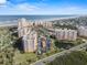 Expansive aerial view showcasing multiple condo buildings, beach access, a community pool, and well-maintained landscaping at 261 Minorca Beach Way # 606, New Smyrna Beach, FL 32169