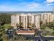 An exterior view of the well-maintained condo building with manicured landscaping, palm trees, and a glimpse of the ocean at 261 Minorca Beach Way # 606, New Smyrna Beach, FL 32169