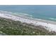 Beautiful aerial view of a sandy beach with gentle waves and scattered parked cars in a scenic coastal setting at 2700 N Peninsula Ave # 113, New Smyrna Beach, FL 32169