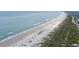 Expansive aerial view captures the beautiful coastline, sandy beach, and adjacent residential area in this coastal landscape at 2700 N Peninsula Ave # 113, New Smyrna Beach, FL 32169
