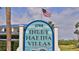 Close-up of the Inlet Marina Villas community signage with an American flag waving above at 2700 N Peninsula Ave # 113, New Smyrna Beach, FL 32169