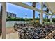 A bike rack full of bicycles sits near tennis courts and benches under a covered area with tropical landscaping at 2700 N Peninsula Ave # 513, New Smyrna Beach, FL 32169