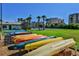 A row of colorful kayaks sit on a rack near a grassy area and tennis courts with tropical landscaping at 2700 N Peninsula Ave # 513, New Smyrna Beach, FL 32169