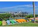 A row of colorful kayaks sits near a waterfront dock filled with various boats on calm water under a blue sky at 2700 N Peninsula Ave # 513, New Smyrna Beach, FL 32169