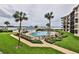 A pool area with palm trees overlooks a waterfront dock with boats and lush landscaping at 2700 N Peninsula Ave # 513, New Smyrna Beach, FL 32169