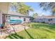 Backyard area featuring a concrete patio, outdoor seating, lush grass, and a wooden fence at 2828 Pine Tree Dr, Edgewater, FL 32141