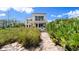 Beautiful home exterior featuring a balcony, lush landscape, pathway, and stunning views of the ocean at 2901 Hill St, New Smyrna Beach, FL 32169
