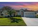 Inviting home exterior with lush landscaping, a well-maintained lawn, and a colorful sunset backdrop at 2908 Cypress Ridge Trl, Port Orange, FL 32128