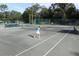 Tennis court with players on court surrounded by a fence and lush greenery at 2908 Cypress Ridge Trl, Port Orange, FL 32128
