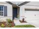 Welcoming front entrance with a gray front door, lovely flowerbeds, and a glimpse of the garage at 3245 Carpentaria Dr, New Smyrna Beach, FL 32168