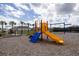 A vibrant playground with a yellow slide, blue climbing wall, swings and monkey bars, set against a bright sky at 3245 Carpentaria Dr, New Smyrna Beach, FL 32168