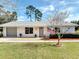 Charming one-story home with a brick exterior, gray accents, manicured lawn and an American flag at 403 Wildwood Dr, Edgewater, FL 32132