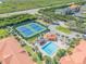 An overhead view shows condos, tennis courts, a pool, and a highway surrounded by lush green landscape at 407 Bouchelle Dr # 205, New Smyrna Beach, FL 32169