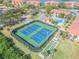 Aerial view of blue tennis courts and shuffleboard courts with lush landscaping and convenient access to a pool at 407 Bouchelle Dr # 205, New Smyrna Beach, FL 32169