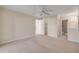 Spacious bedroom with neutral carpeting and a ceiling fan, leading to bathroom with step-in shower at 407 Bouchelle Dr # 205, New Smyrna Beach, FL 32169